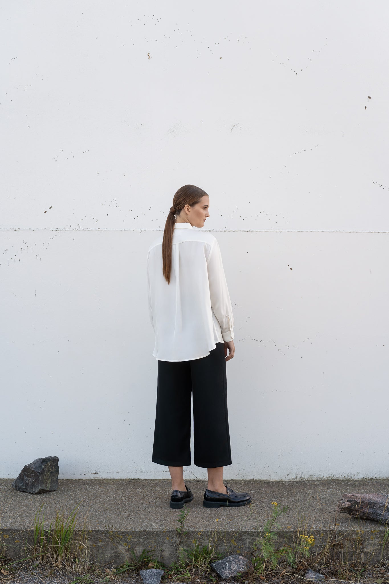 Ivory silk shirt and black wool culottes on a model.