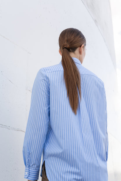 A mode wearing fresh, light blue button up shirt back to the camera.
