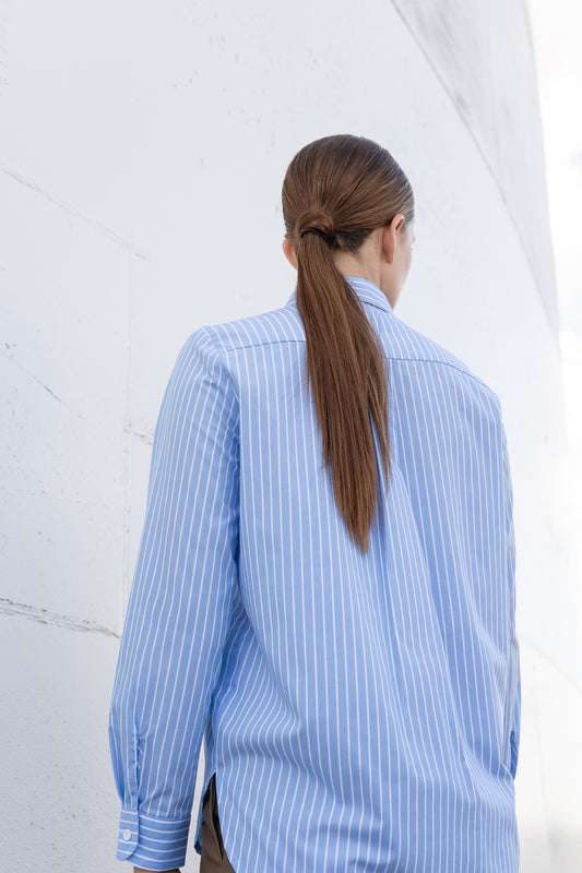 A mode wearing fresh, light blue button up shirt back to the camera.